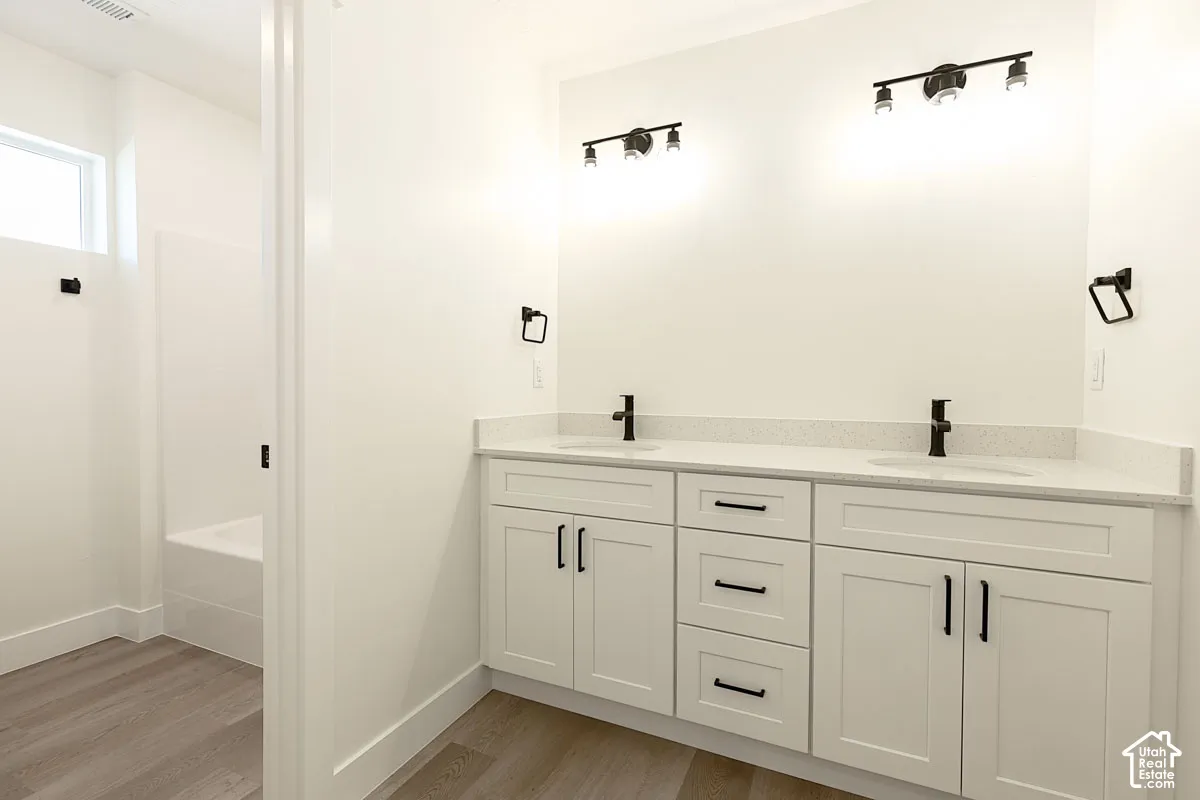 Dual vanity with white cabinetry, matte black hardware, and speckled light-colored countertops