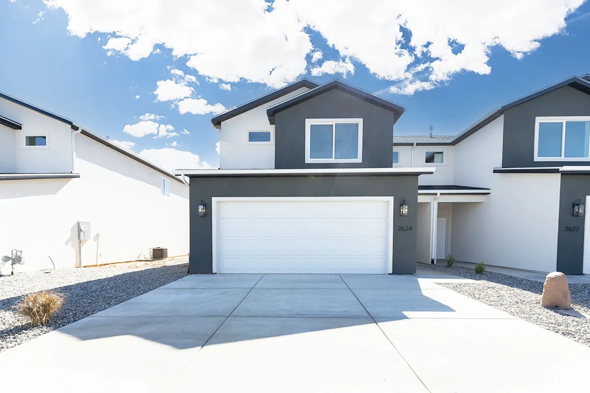 Contemporary stucco exterior with contrasting trim, integrated garage, concrete driveway, and exterior lighting fixtures