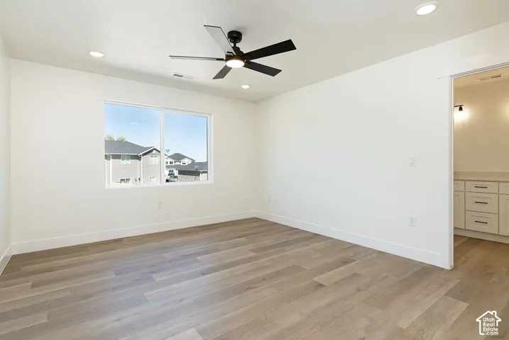 Recessed ceiling lighting, a modern ceiling fan, wood-finish flooring, and a large window
