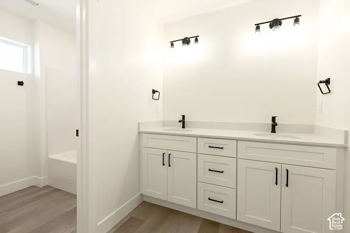 Dual vanity with white cabinetry, matte black hardware, and speckled light-colored countertops