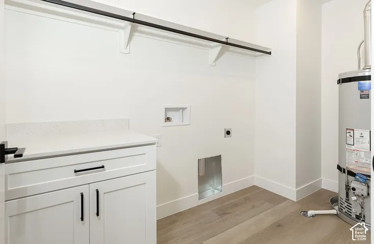 White cabinetry with matte black hardware, light-toned wood-finish flooring, and a stone-finish countertop