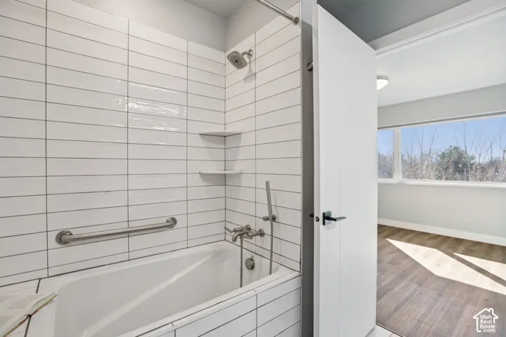 Bathtub with white subway tile surround, integrated corner shelving, and stainless steel fixtures