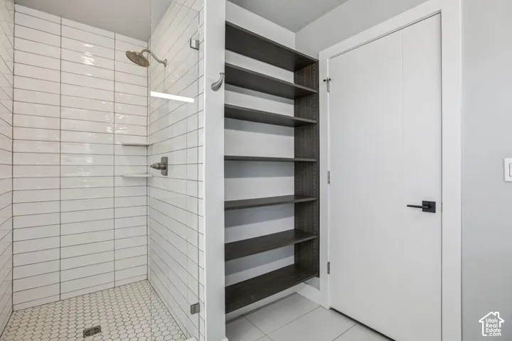 Walk-in shower with horizontal white tile, hexagonal floor tile, built-in shelving, and a frameless glass enclosure
