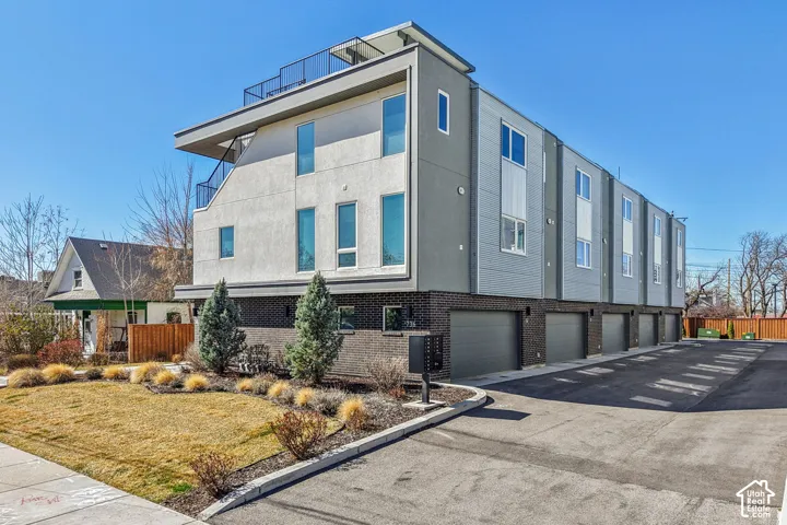 Contemporary exterior with multiple garage bays, a rooftop deck, and a landscaped frontage