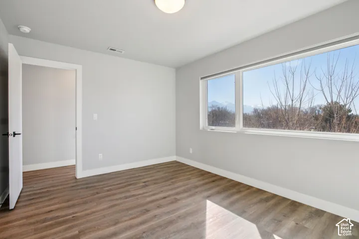 Wood-finish flooring, white trim, light gray painted walls, and a large window with a mountain backdrop