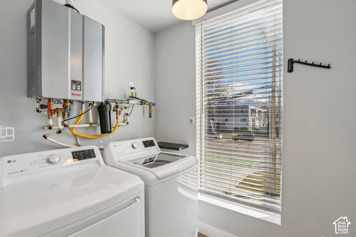 Laundry space featuring a wall-mounted water heater, a window with horizontal blinds, and a wall-mounted drying rack