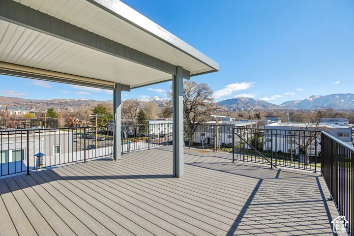 Expansive rooftop deck featuring composite decking, a partial overhead patio cover, and black metal railings