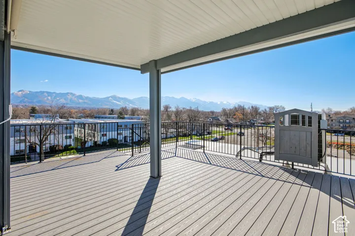 Covered outdoor deck with composite decking, black metal railing, and a mountain backdrop