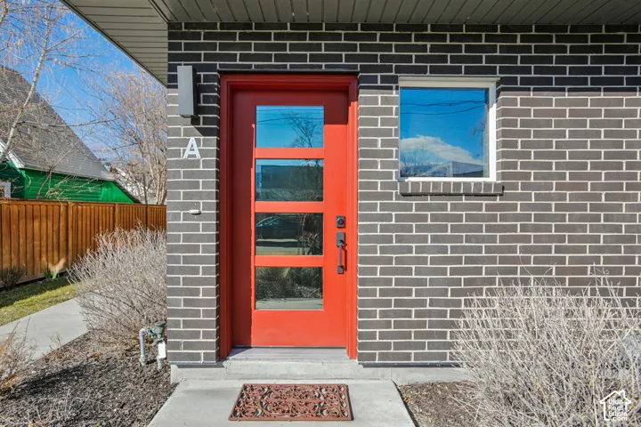 Contemporary facade featuring dark brickwork and a vibrant red entry door with multiple glass inserts