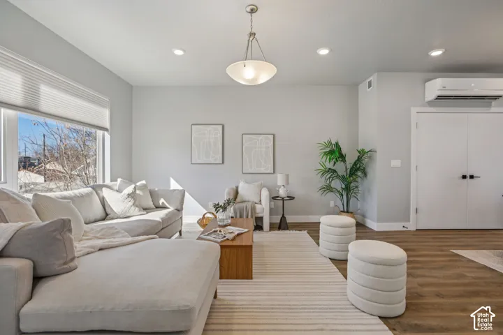Spacious living area featuring wood-finish flooring, recessed lighting, and large windows with cellular shades