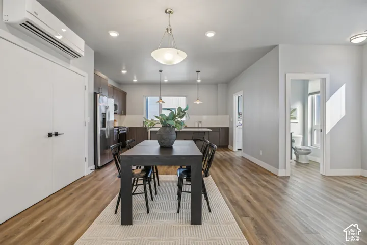 Open-concept living area featuring wood-finish flooring, recessed lighting, and a modern kitchen with dark cabinetry and stainless steel appliances