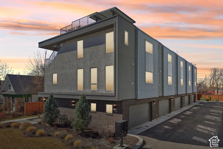 Multi-level townhome exterior with mixed material facade, private roof deck, and attached garages