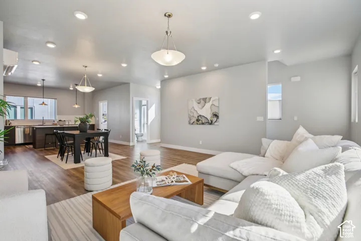 Open-concept living space featuring wood-finish flooring, recessed lighting, and pendant fixtures