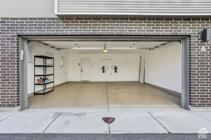 Spacious garage with an epoxy-coated concrete floor, featuring a side access door and integrated lighting