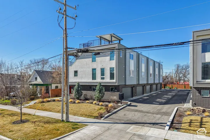 Modern townhome architecture featuring a flat roofline, an integrated garage, and a rooftop deck