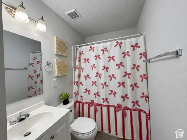 Vanity with a white basin sink and chrome faucet, wall-mounted mirror, and overhead vanity lighting