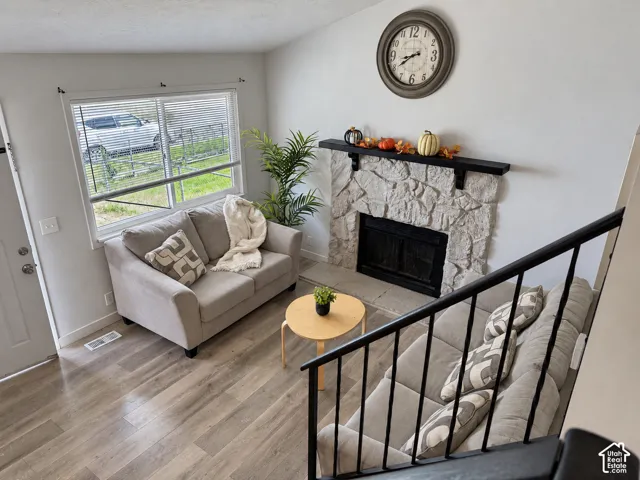 Stone-faced fireplace with a black mantel, wood-finish flooring, and white walls