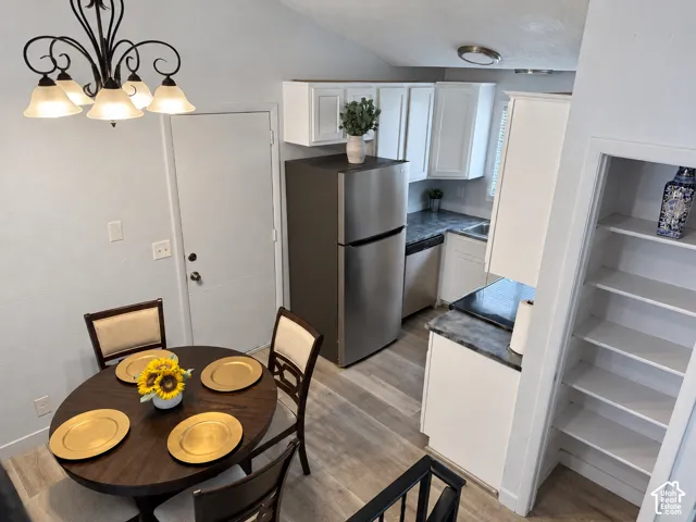 Kitchenette featuring white cabinetry, dark stone-finish countertops, stainless steel appliances, and integrated shelving