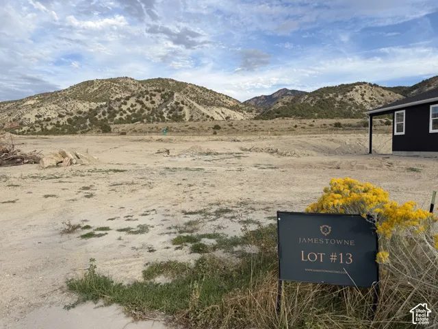 Expansive lot with mountain scenery, featuring a partial structure with a dark facade and white-framed windows