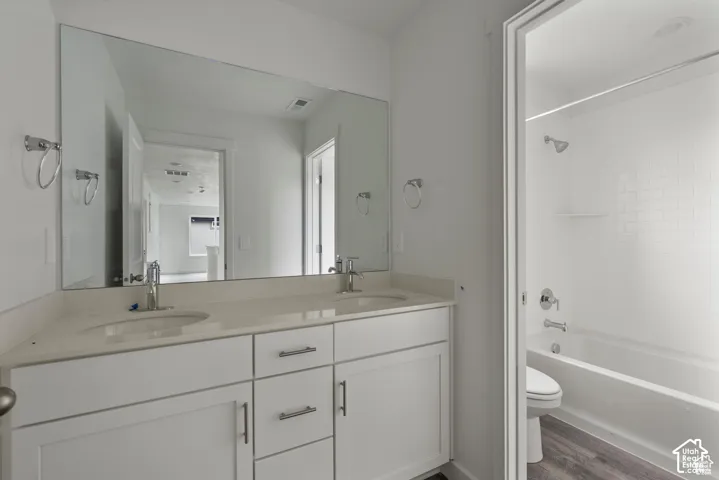 Dual vanity with integrated sinks, expansive wall-mounted mirror, white shaker-style cabinetry, and chrome fixtures