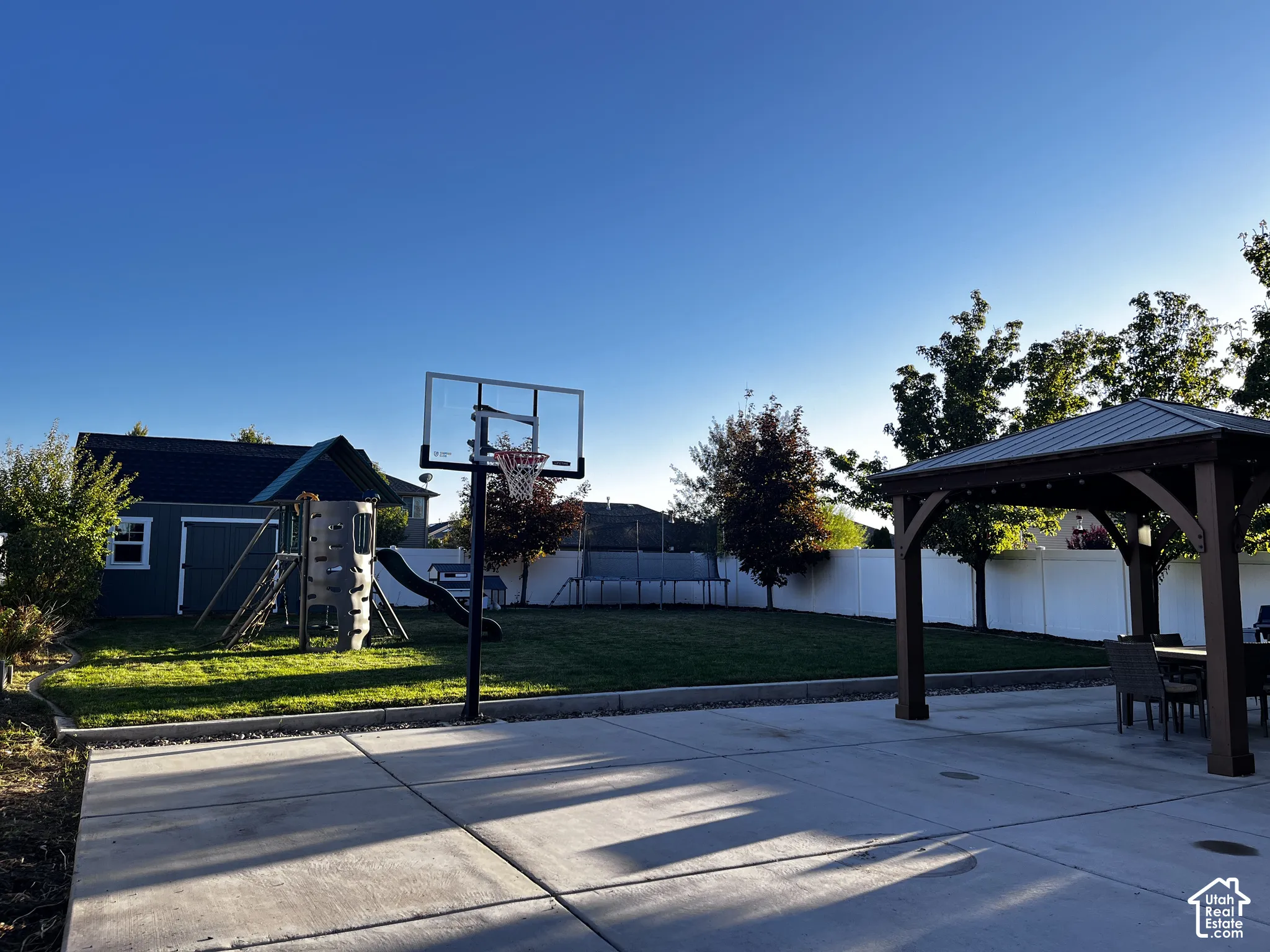 Expansive concrete patio with a permanent basketball hoop and a built-in gazebo