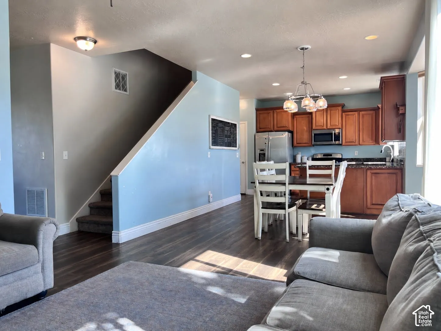 Open-concept living area with wood-finish flooring, a full kitchen featuring wood cabinetry, stainless steel appliances, and a dining area