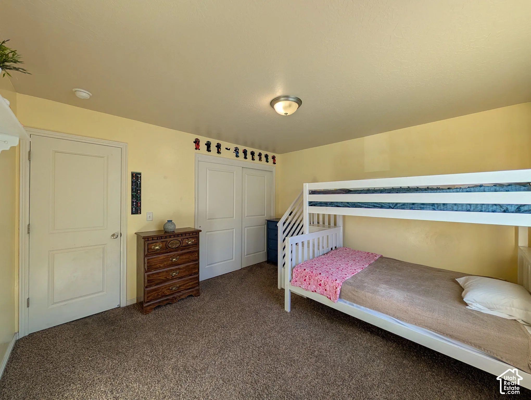 Wall-to-wall carpeting with a neutral finish, interior door with paneling, and sliding closet doors