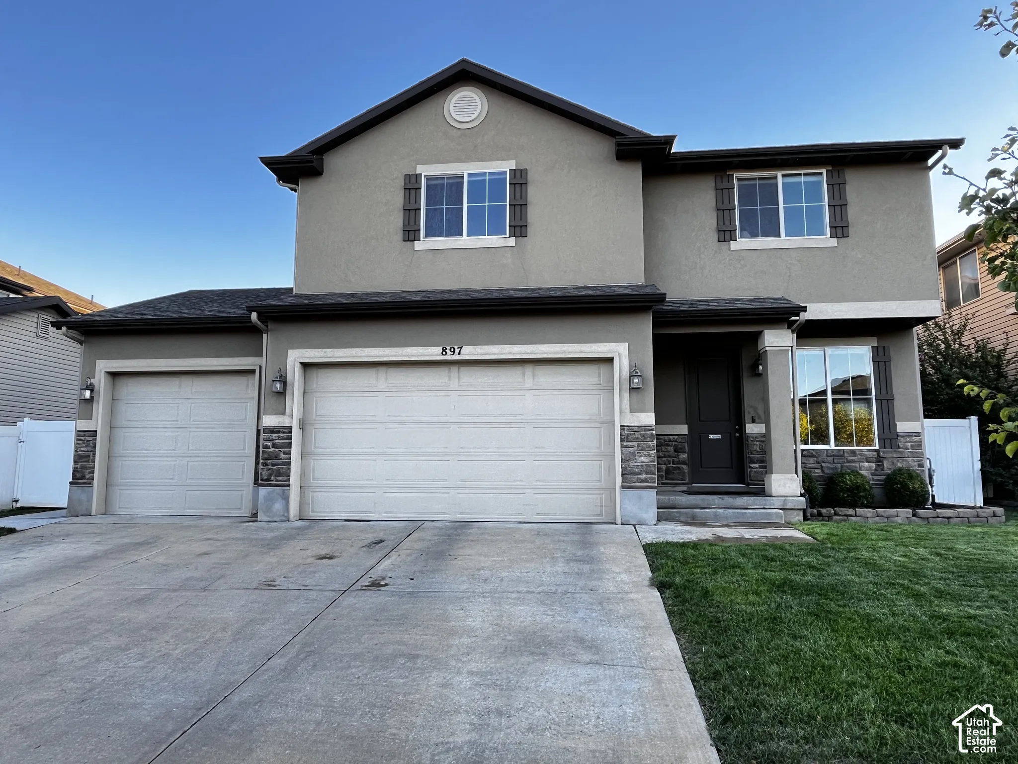 Stucco exterior with stone accents and dark trim, fully landscaped with a 3-car garage