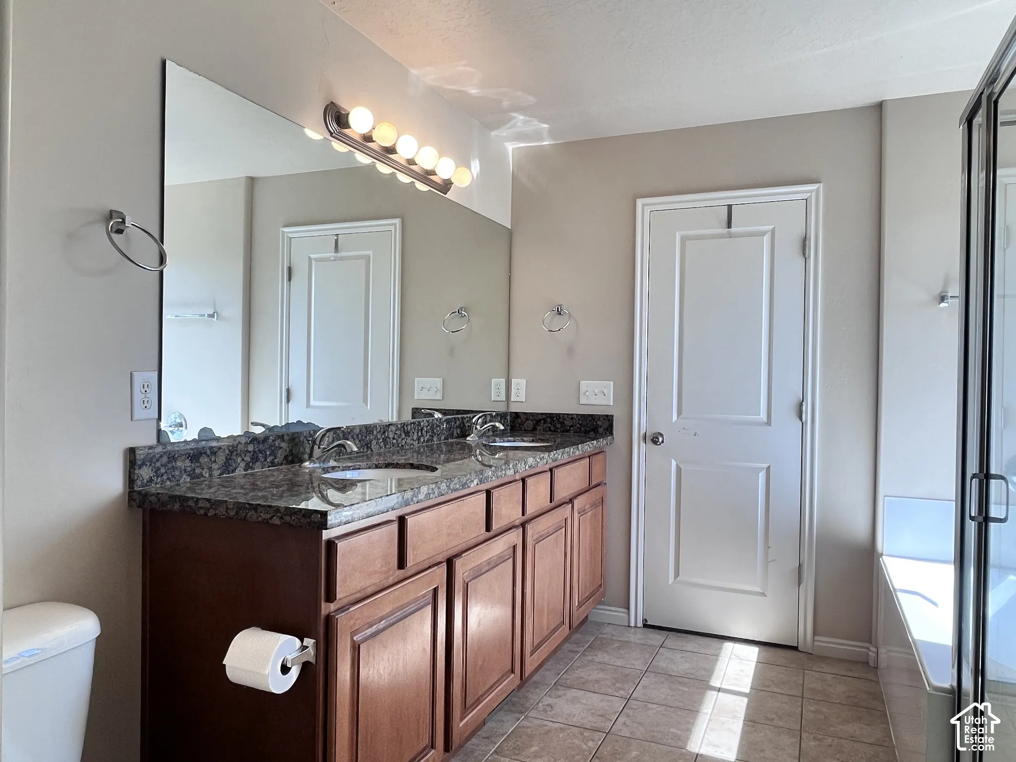 Dual vanity with a dark wood-finish cabinet and dark stone-finish countertop