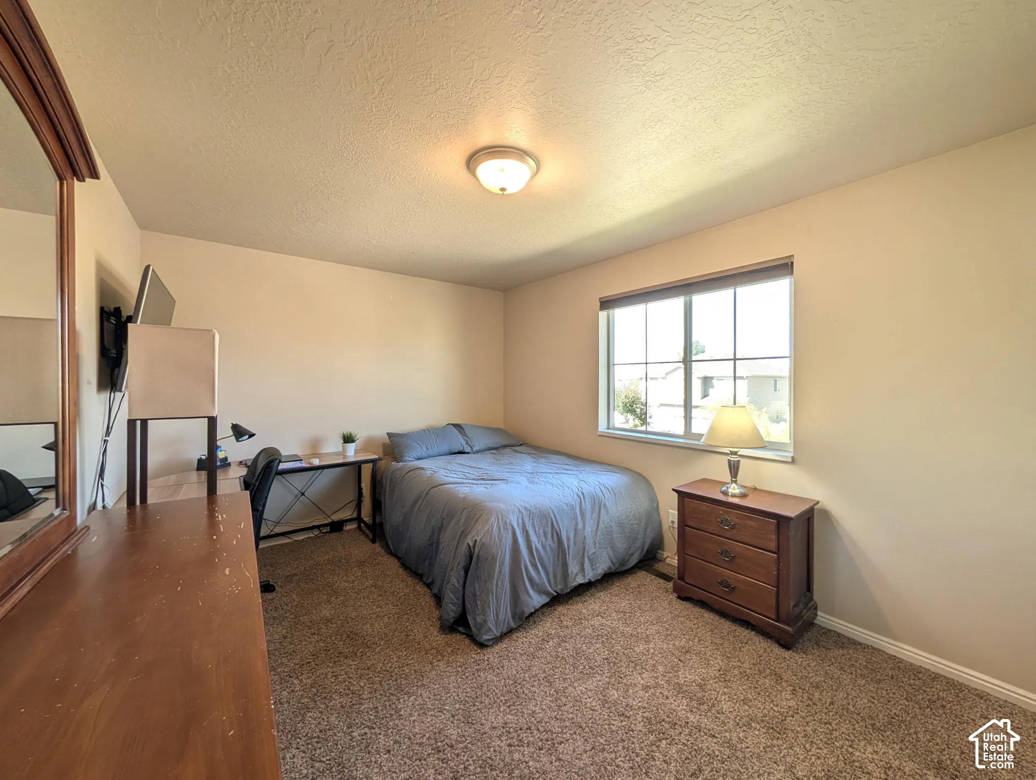 Neutral wall color, wall-mounted light fixture, carpeted flooring, and a large window