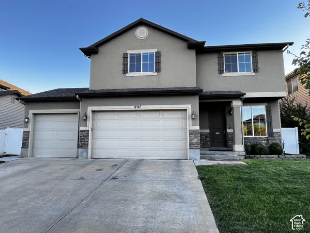 Stucco exterior with stone accents and dark trim, fully landscaped with a 3-car garage