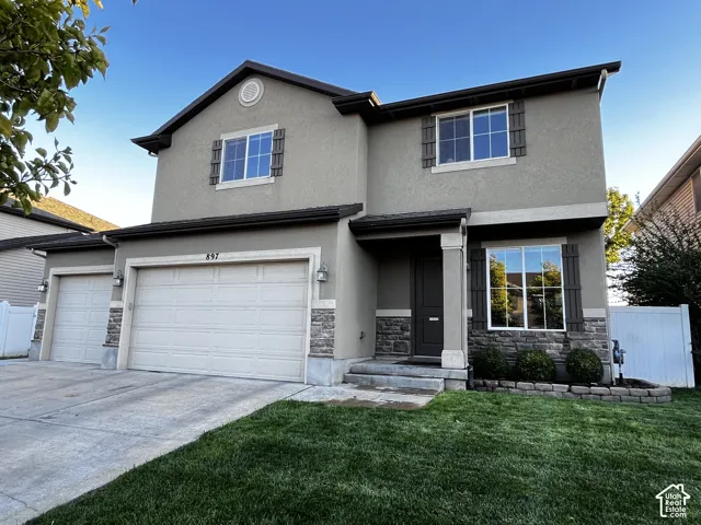 Two-story stucco facade featuring decorative stone accents, dark-stained shutters, and a three-car garage
