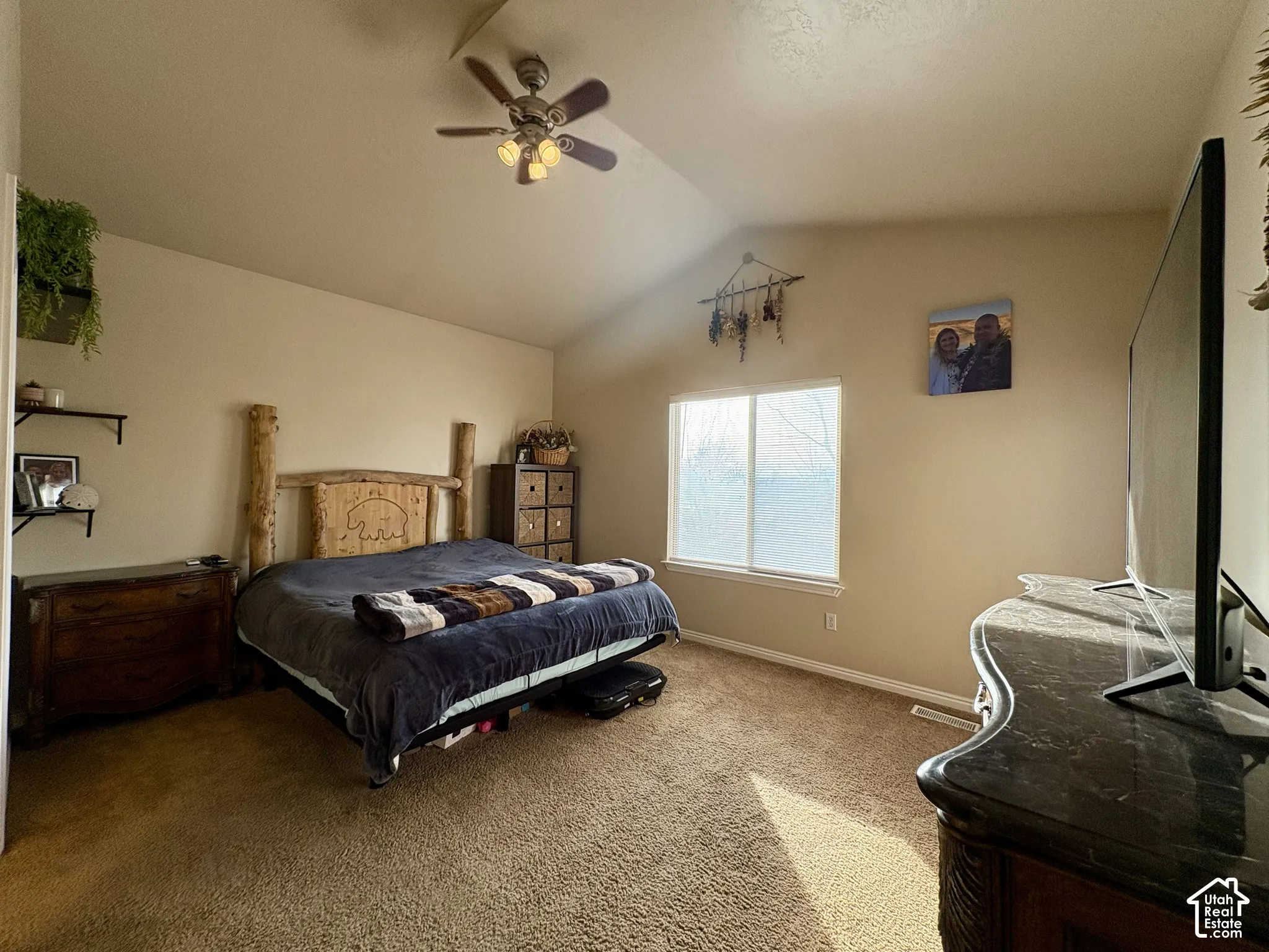 Vaulted ceiling with an attached ceiling fan, single window, and carpeted flooring