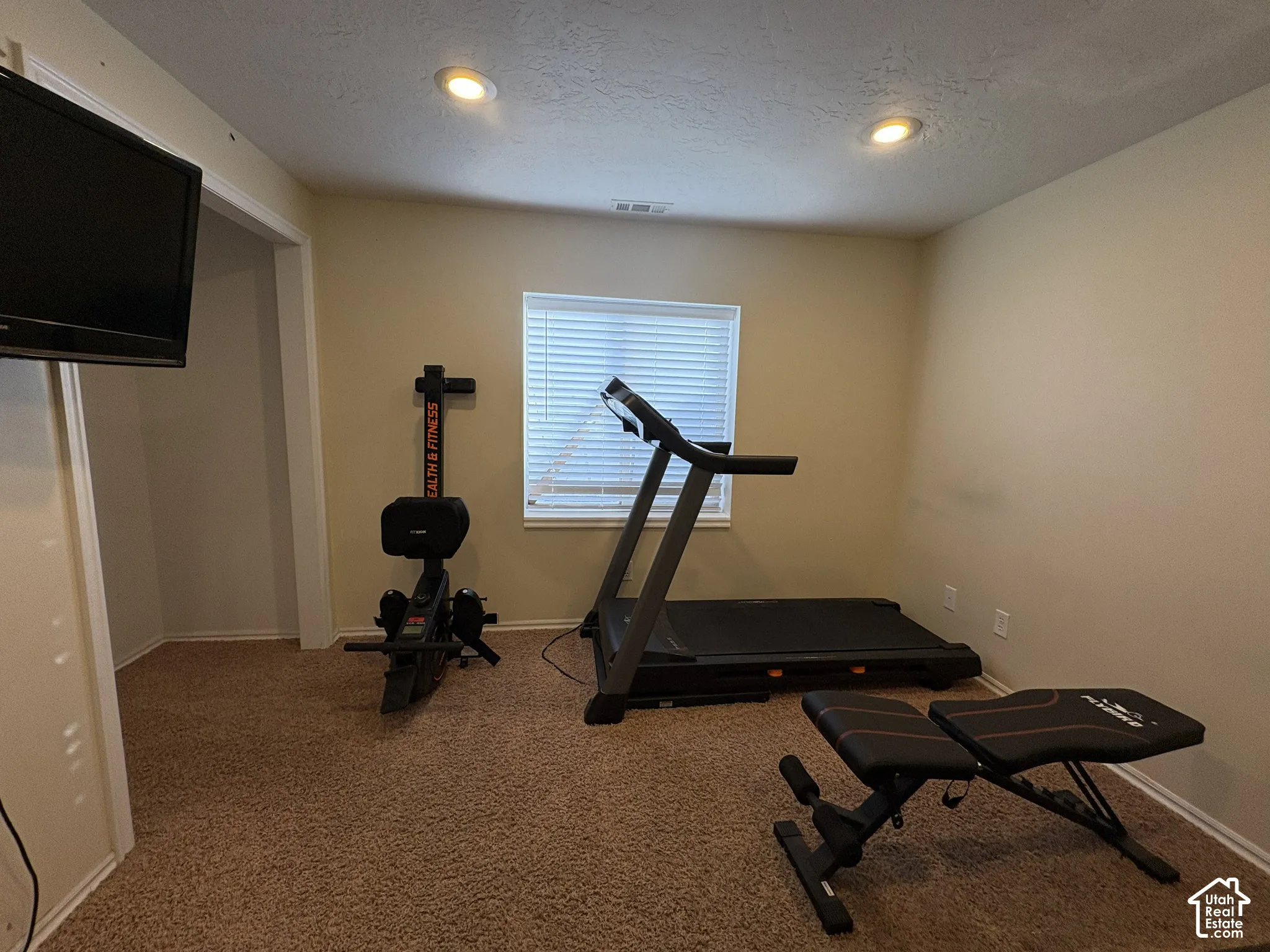 Recessed ceiling lighting, textured wall finish, and a window with horizontal blinds