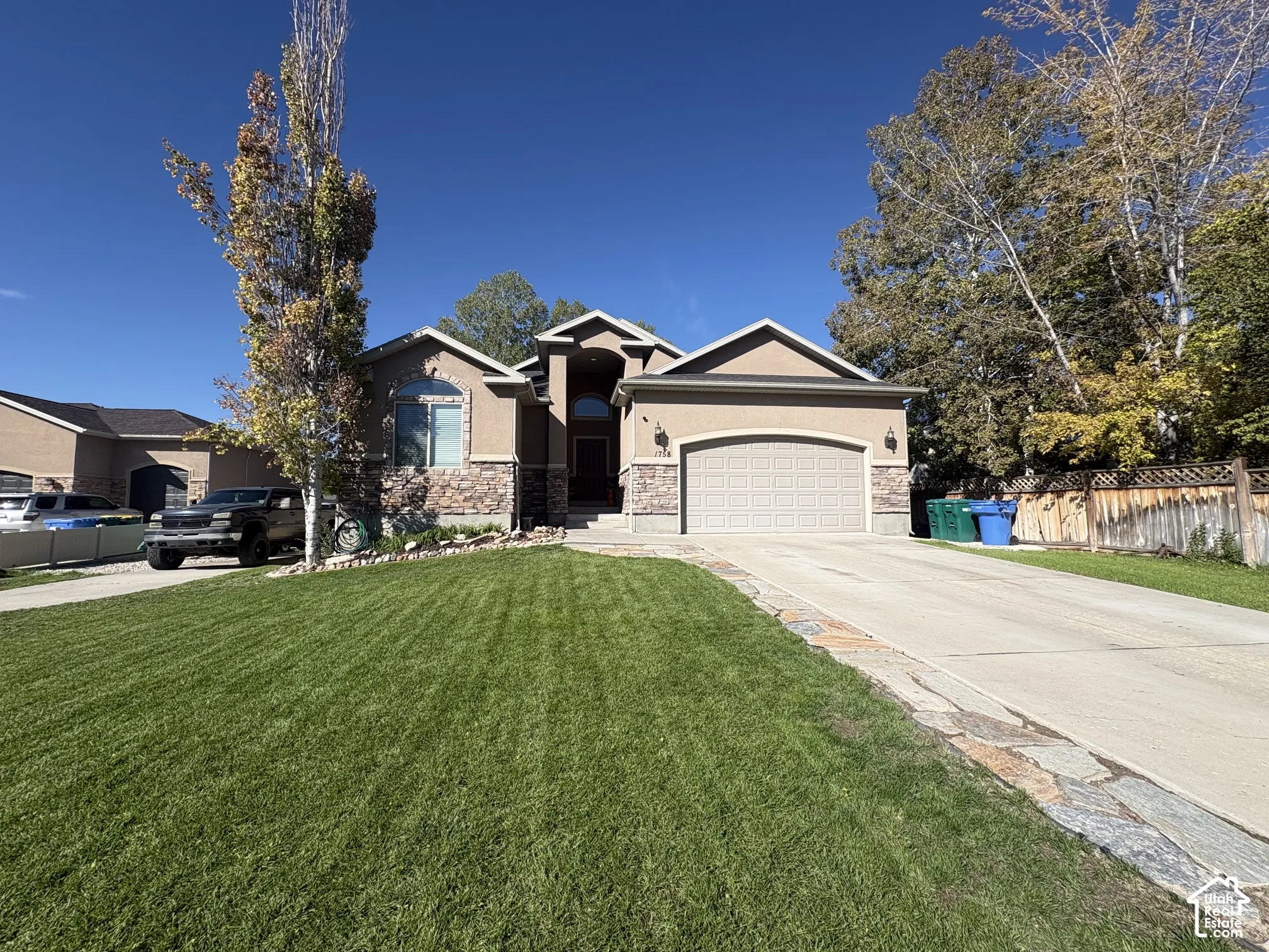 Stucco exterior featuring stone accents, an arched entry, and an integrated garage