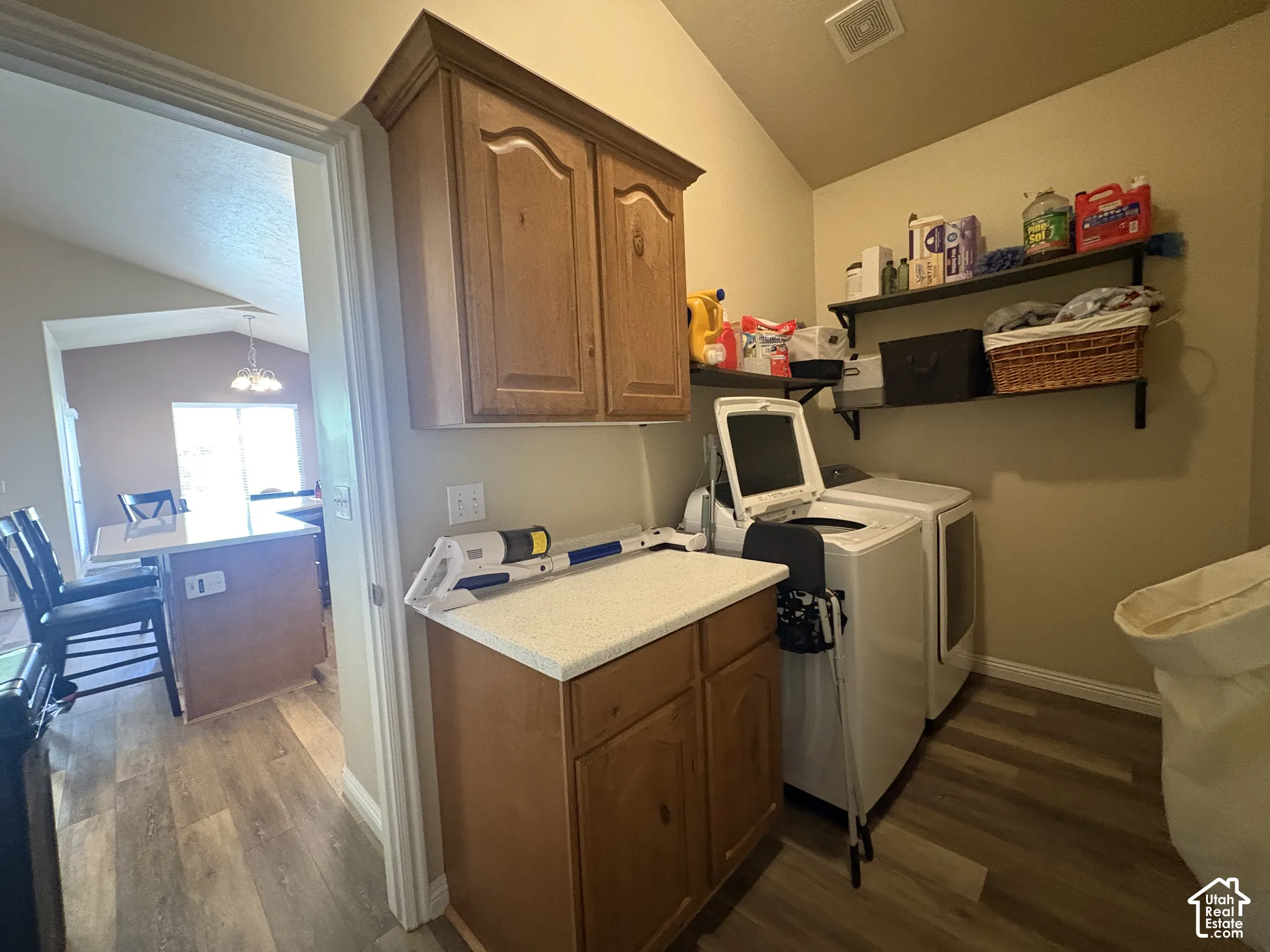 Laundry area featuring wood-finish flooring, built-in cabinetry, and wall-mounted shelving