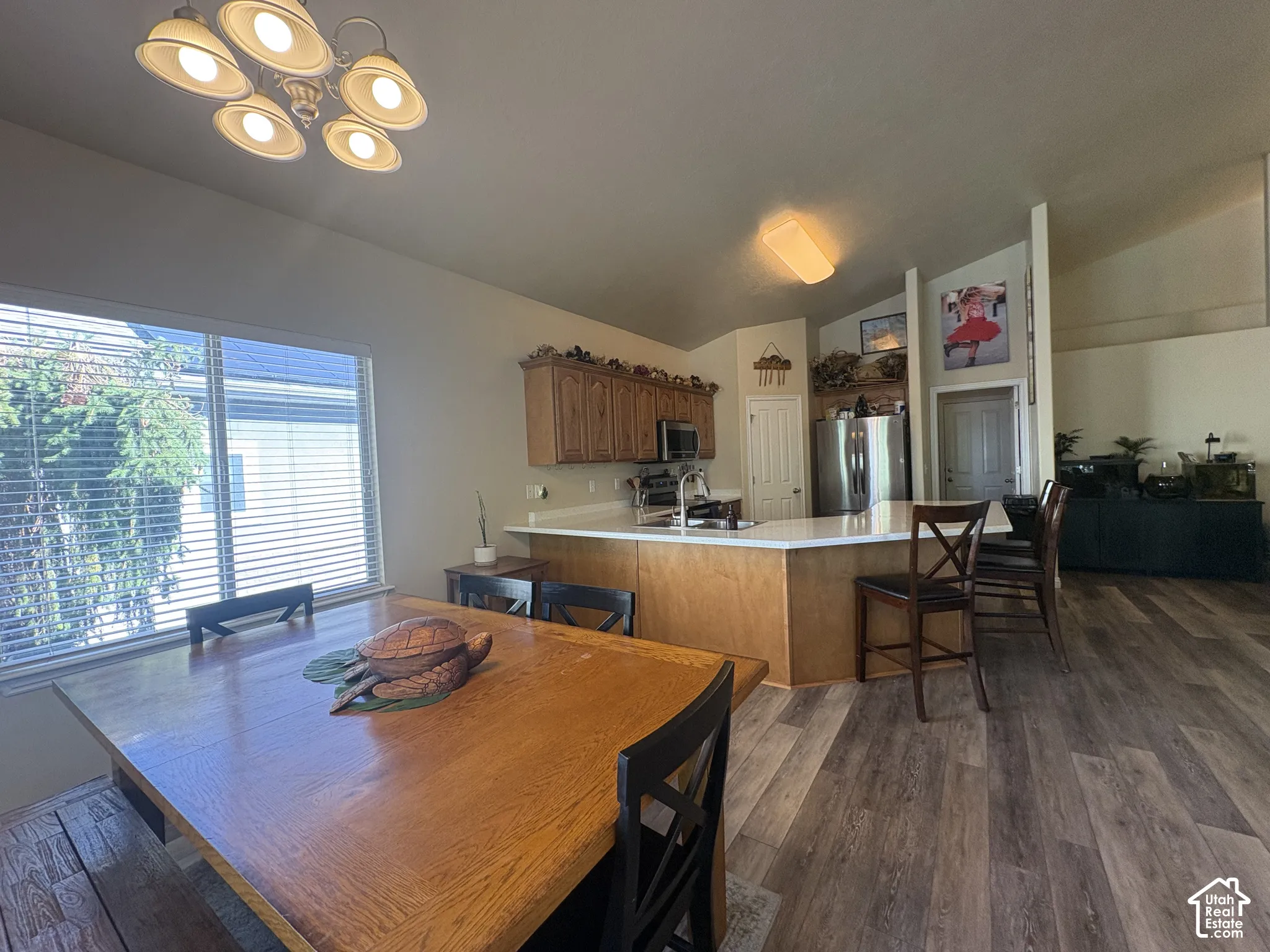 Open concept living space featuring wood-finish flooring, vaulted ceilings, and natural light from a large window