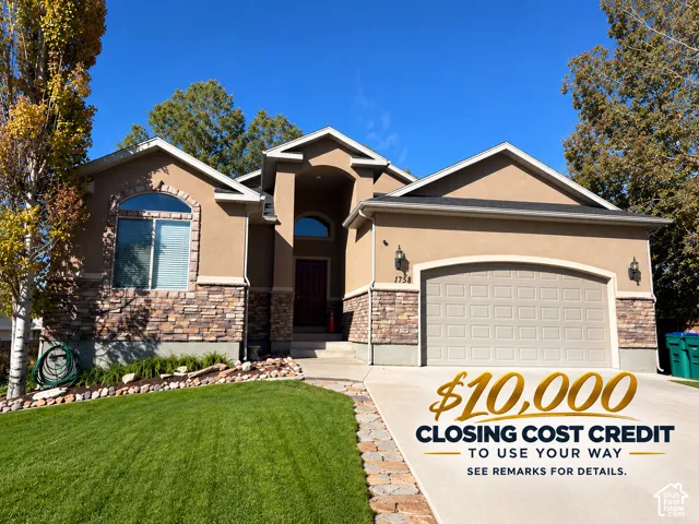 Stucco exterior with stone accenting, arched entry, paved driveway, and attached garage