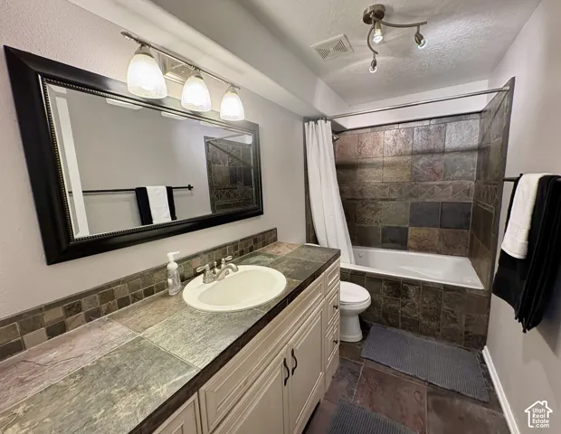 Bathroom featuring a large vanity with an integrated sink, mosaic tile backsplash, and a framed mirror