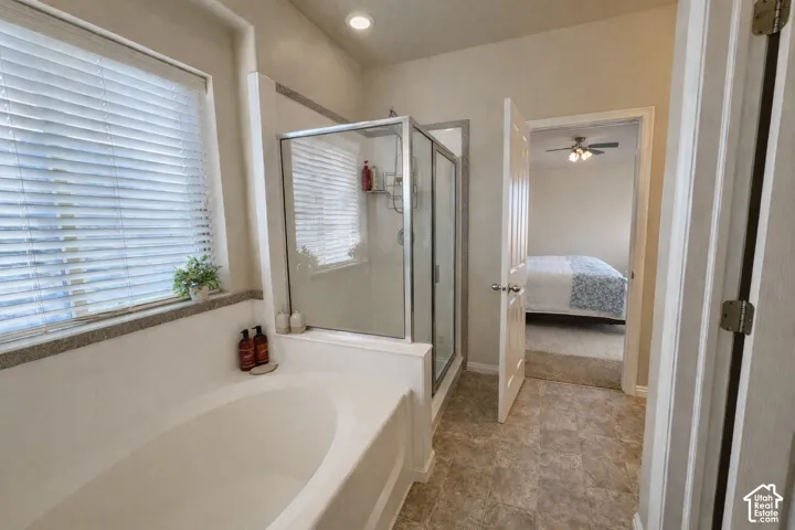 Soaking tub and a glass-enclosed shower with tile flooring