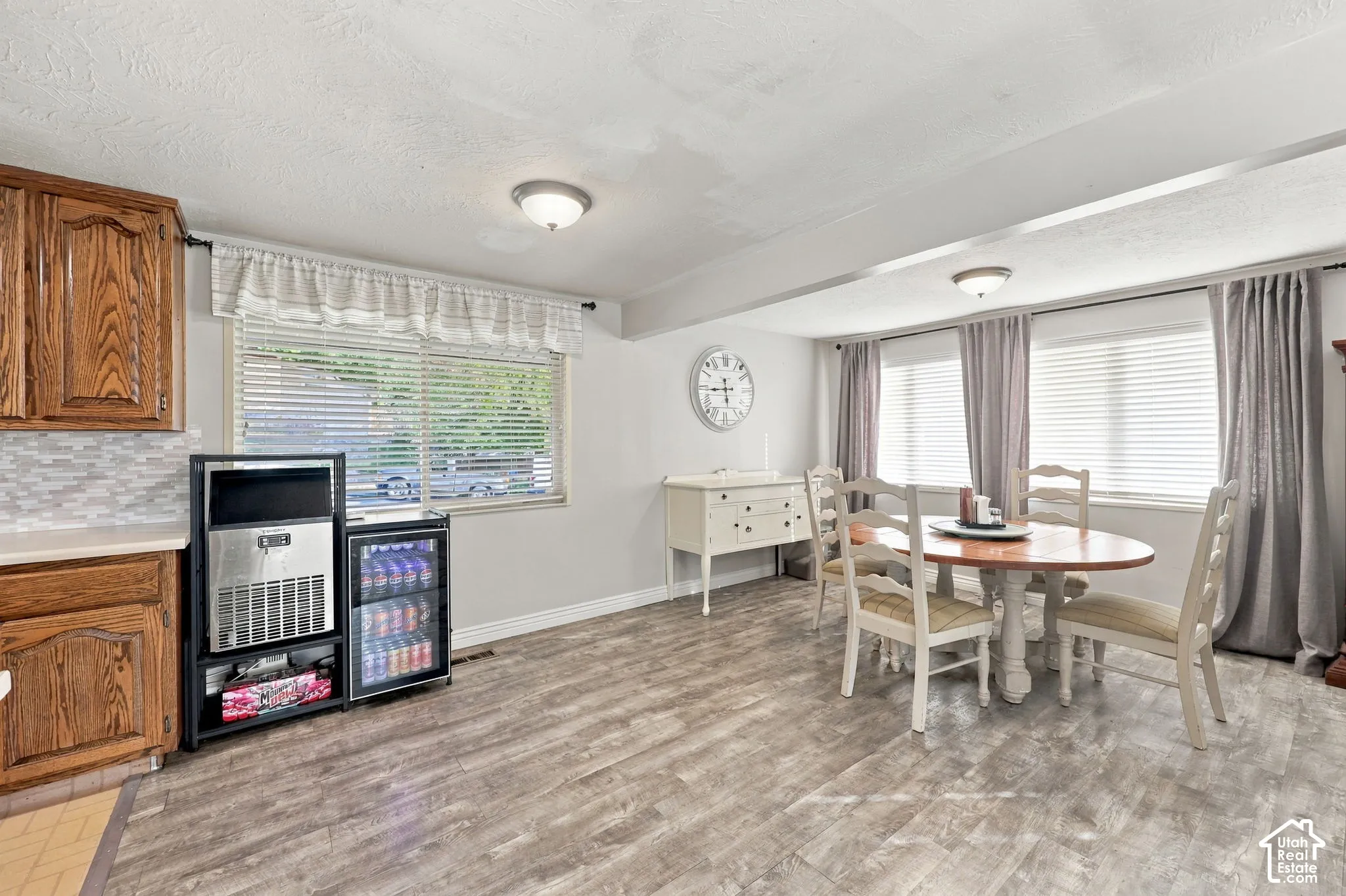 Wood-finish flooring throughout, light wood cabinetry, and a tile backsplash
