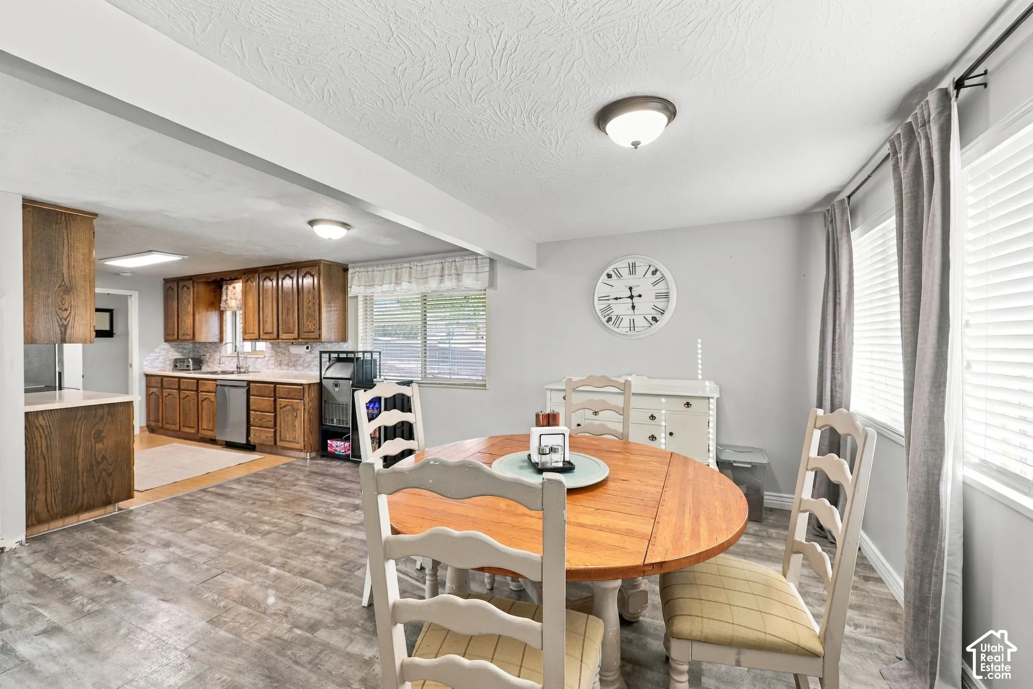 Wood-finish flooring throughout, with a functional kitchen featuring wood cabinetry, stainless steel appliances, and light-toned countertops