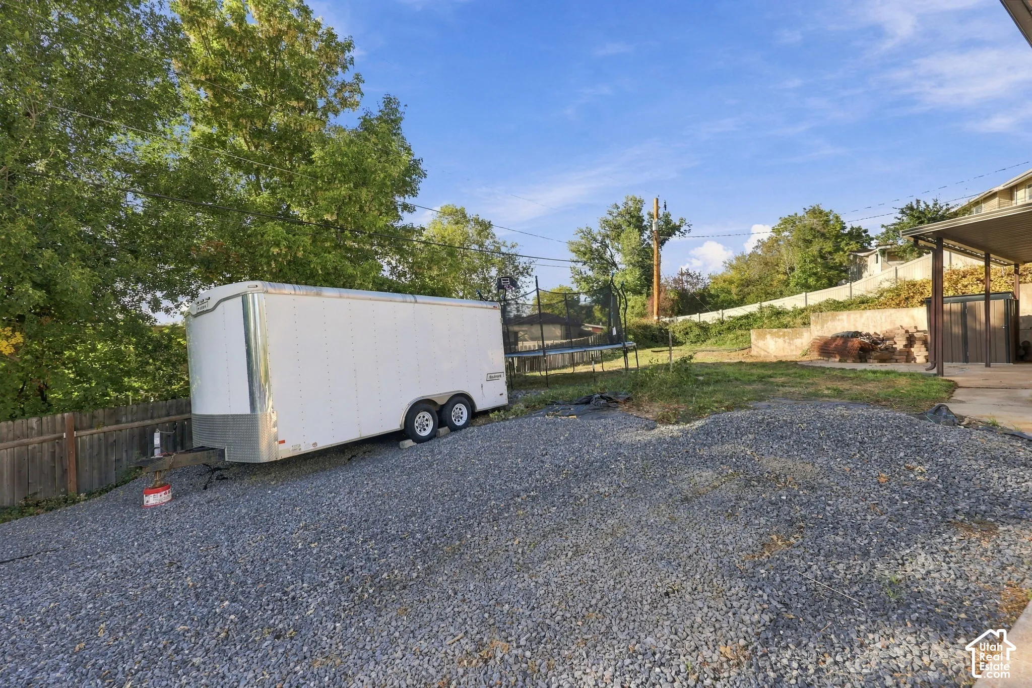Gravel parking area, grassy expanse, and mature trees creating a natural perimeter