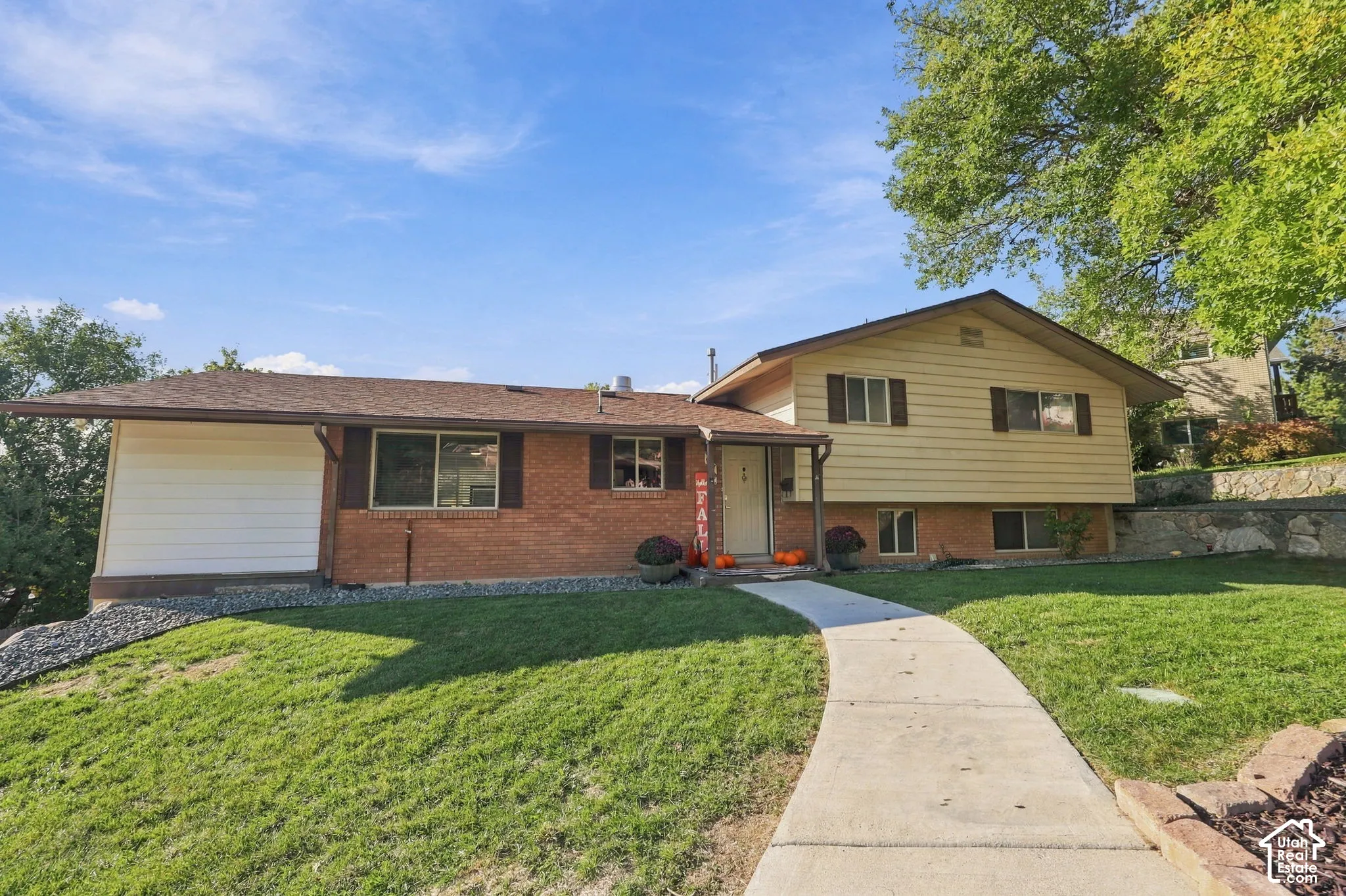 Brick and siding exterior with a pitched roof and a concrete pathway