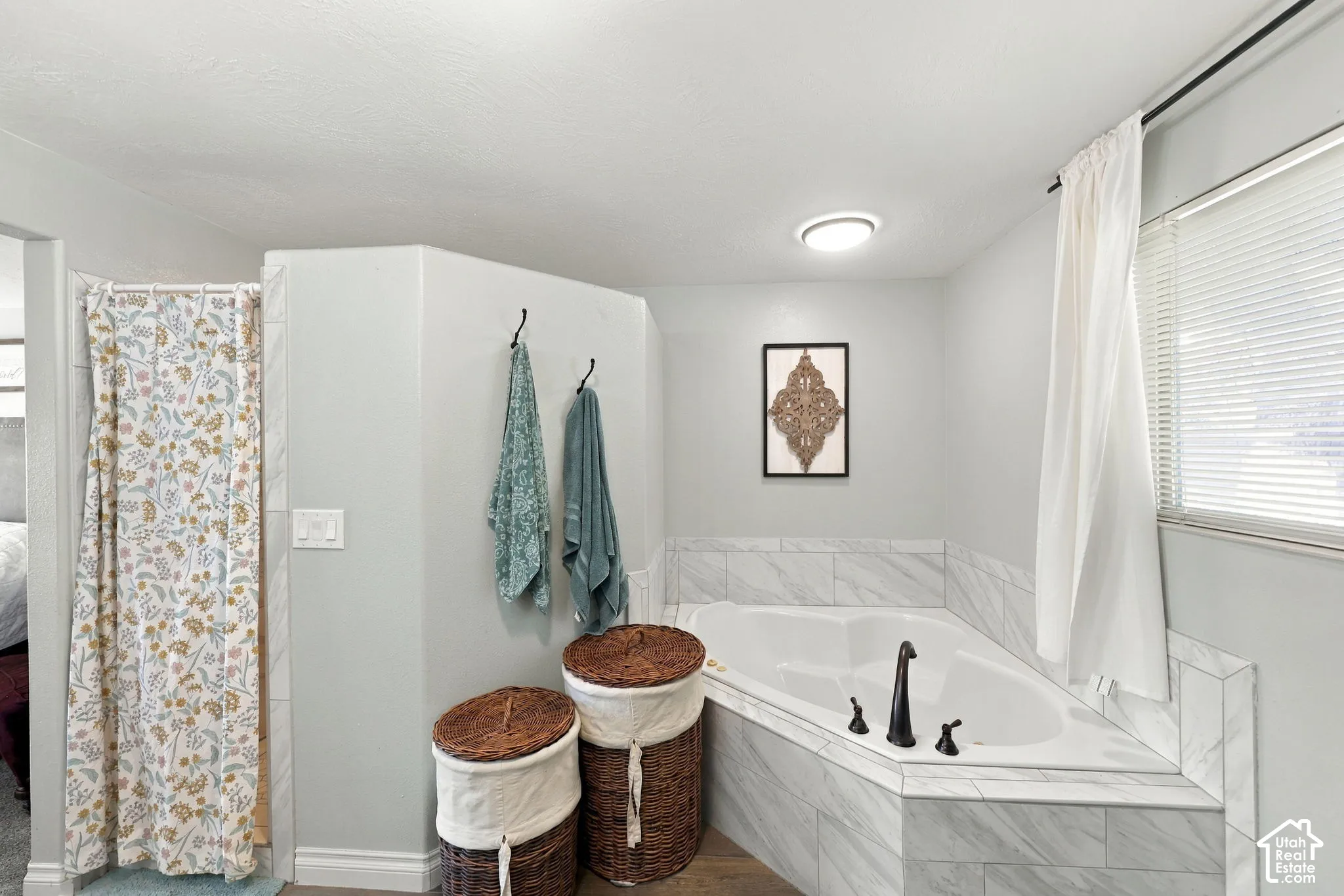 Corner soaking tub with dark bronze fixtures, surrounded by tile-finish paneling