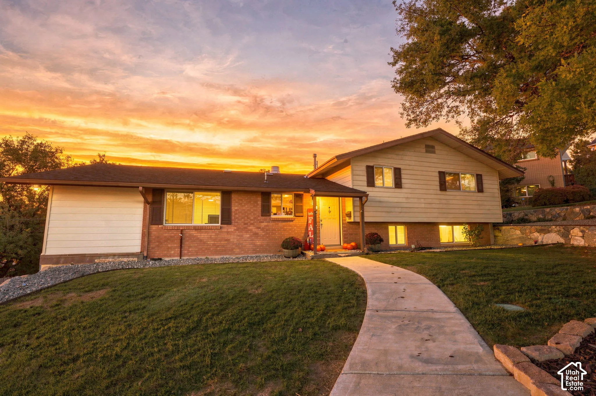 Exterior view of single family home, brick and siding facade, covered front entry, attached garage, and a concrete walkway