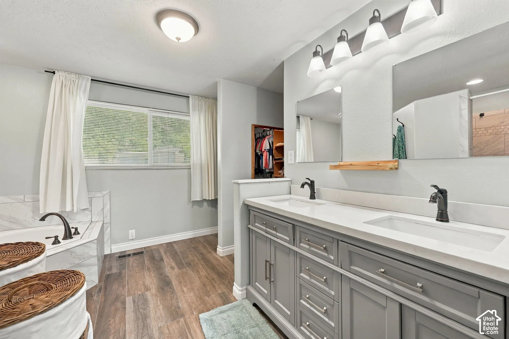 Dual vanity in primary suite bathroom with separate tub and shower