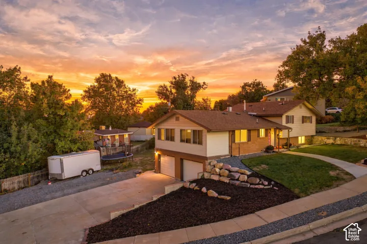 Single family home on corner lot featuring an attached two-car garage, concrete driveway, and landscaped front yard with a stone retaining wall