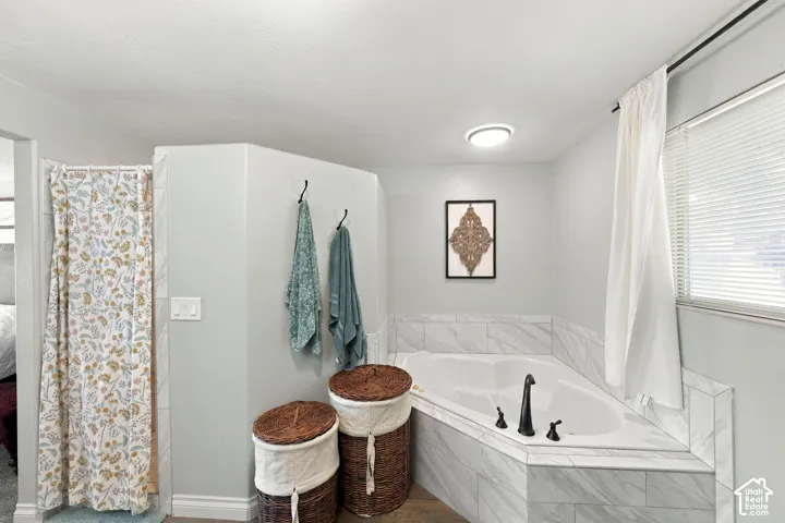 Corner soaking tub with dark bronze fixtures, surrounded by tile-finish paneling