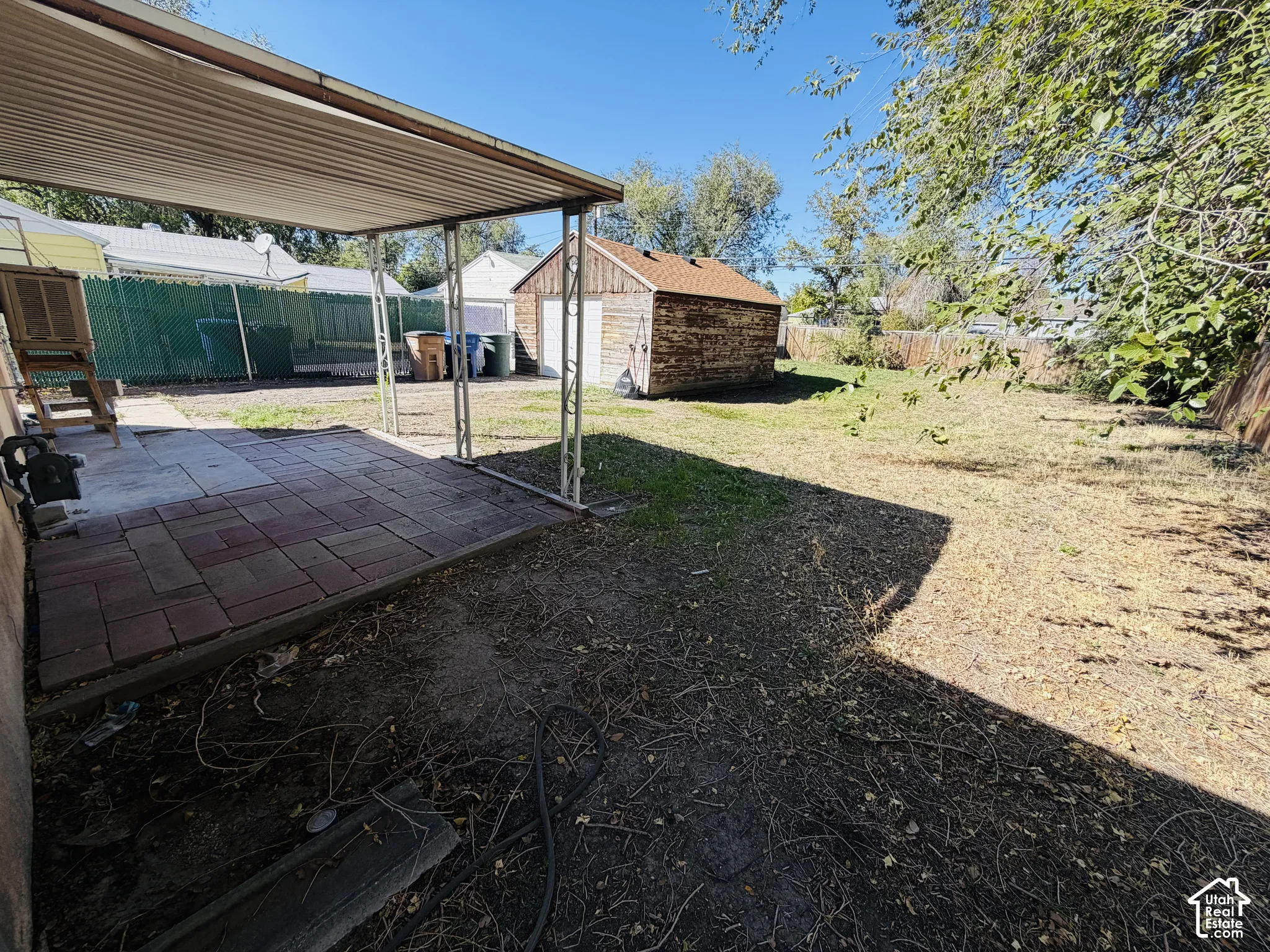 Patio with a metal awning, paver flooring, spacious yard, and a detached shed